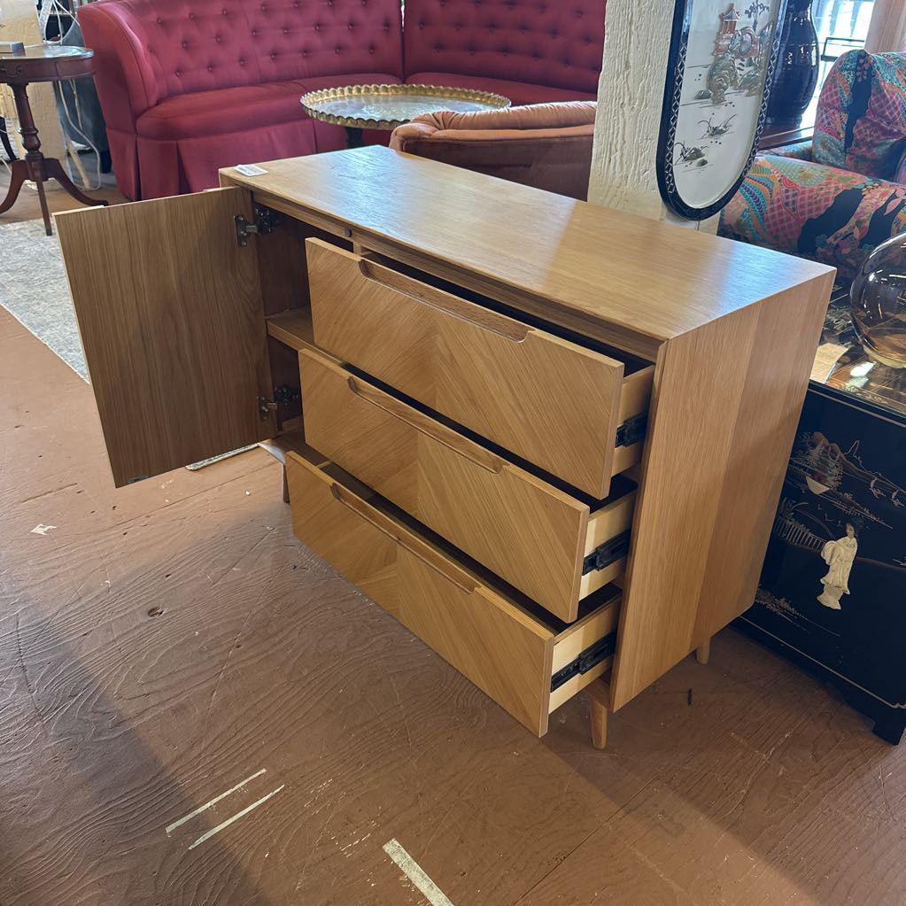 Wooden sideboard with open cabinet door in a room with furniture and decor.