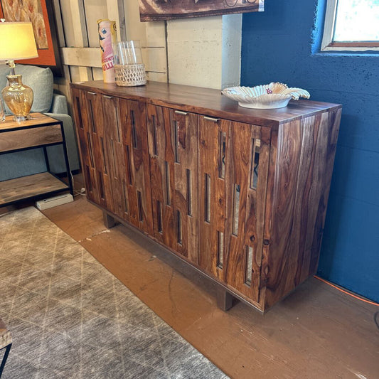 Wooden sideboard in a room with a blue wall and a lamp on a table.