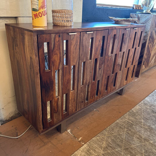 Wooden sideboard with geometric cut-out design in a room setting.