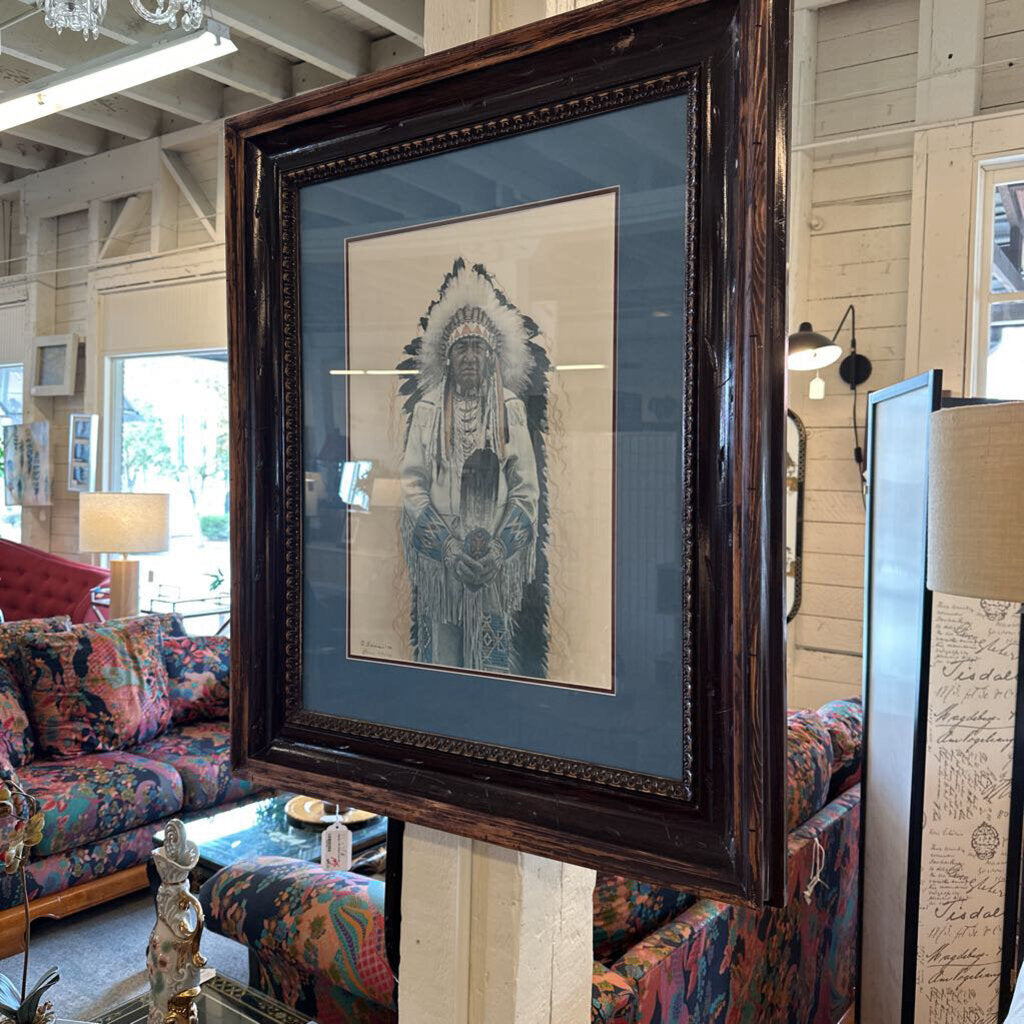 Framed artwork of a Native American figure in a room with colorful furniture.
