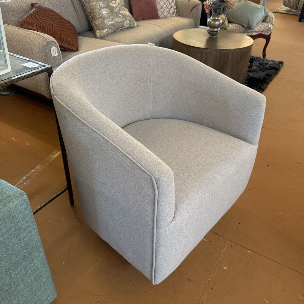 Gray armchair in a living room setting with a couch and coffee table in the background.