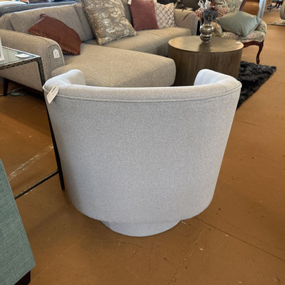 Gray armchair in a showroom setting with a brown floor.