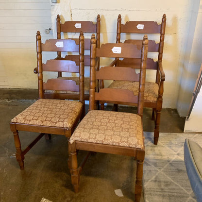 Set of wooden chairs with patterned seats in a room with a striped carpet and white walls.