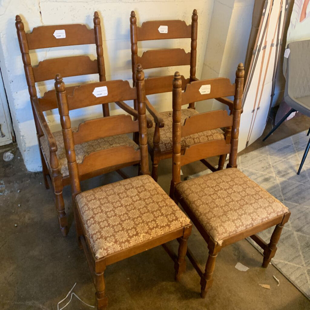 Set of wooden chairs with patterned seats in a storage or warehouse setting.