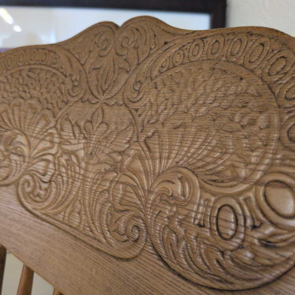 Close-up of a wooden surface with intricate carvings and a visible brand logo.