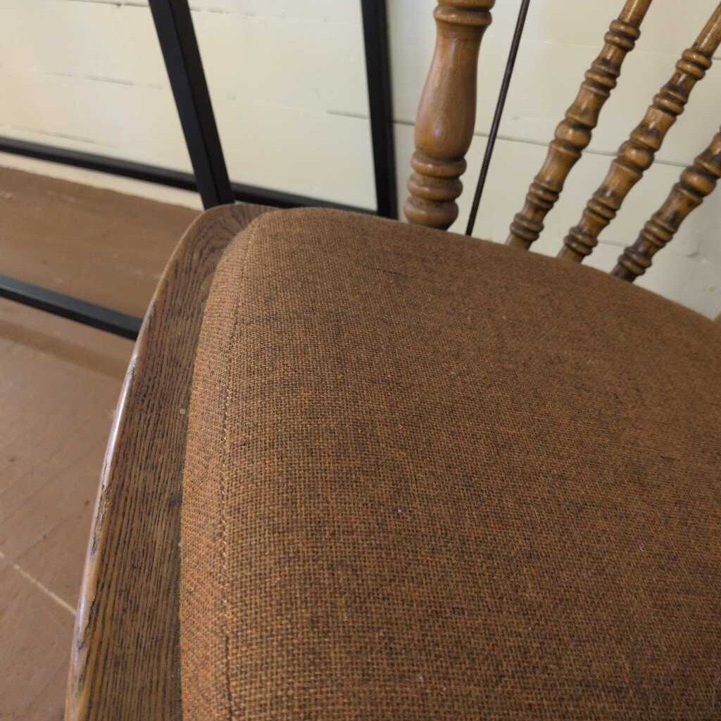 Brown upholstered chair with wooden backrest on a tiled floor