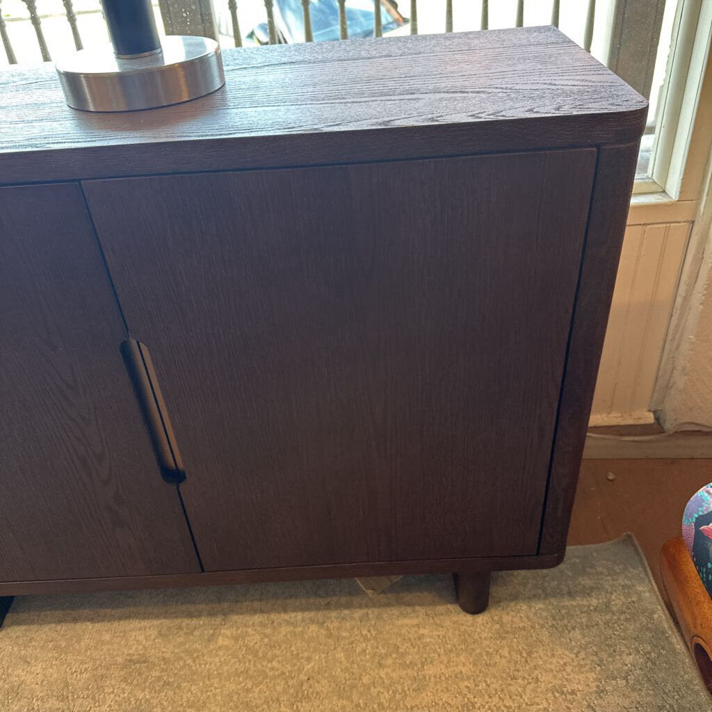 Dark wooden cabinet with metal handles in a room setting