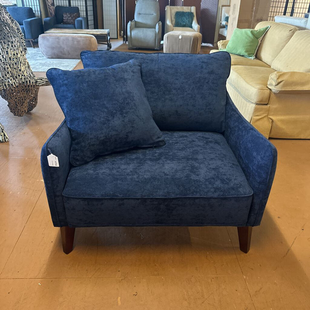 Blue armchair with a pillow in a showroom setting