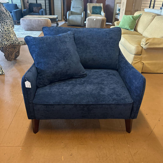 Blue armchair with a pillow in a showroom setting