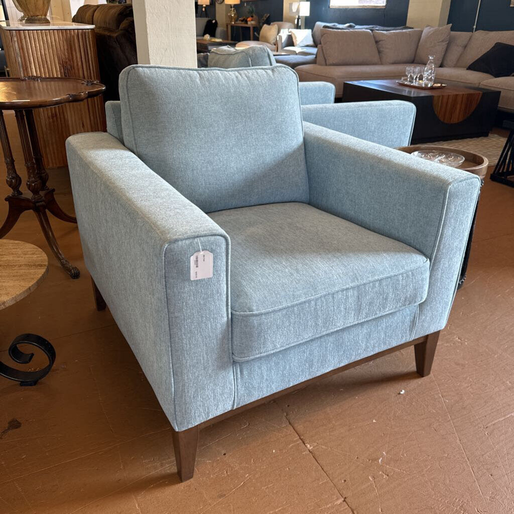 Blue armchair in a showroom setting with other furniture in the background