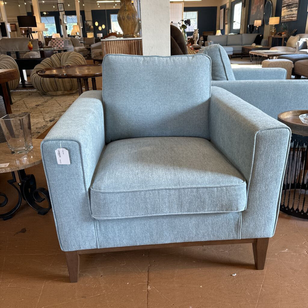 Blue armchair in a showroom setting with other furniture and decor.