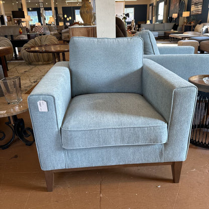 Blue armchair in a showroom setting with other furniture and decor.