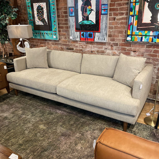 Gray sofa in a room with colorful artwork on the wall.