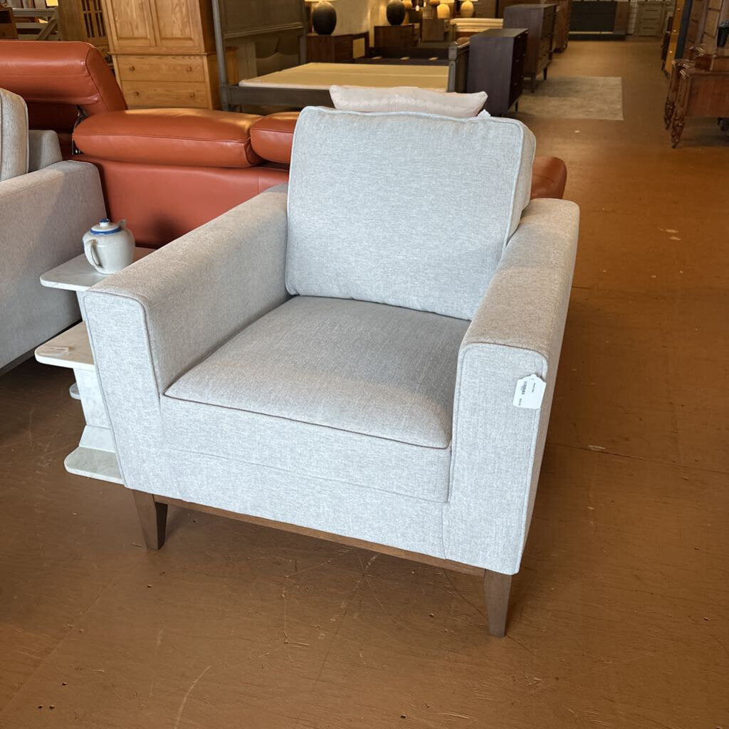 Gray armchair with a small table and mug in a furniture store setting