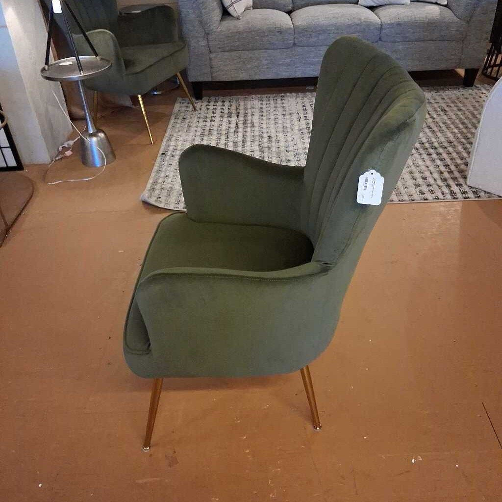 Green chair with a price tag on a wooden floor in a room with a sofa and rug.