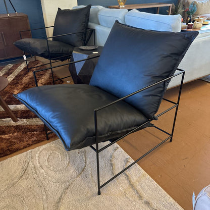 Modern black chair with blue cushions in a living room setting