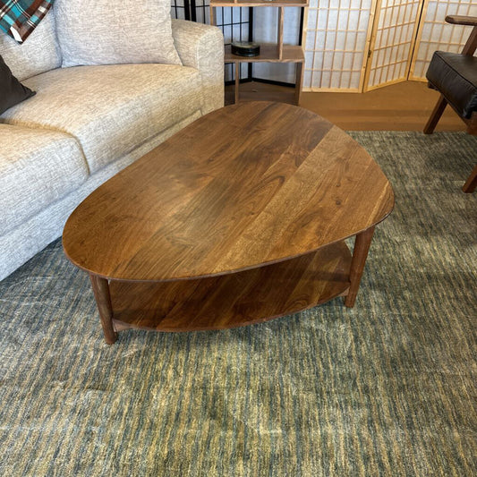 Wooden coffee table in a living room setting with a sofa and decorative items.