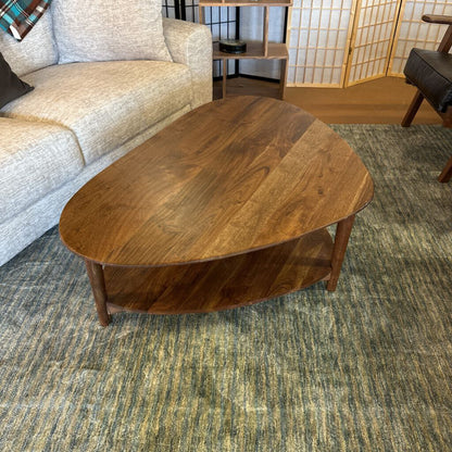 Wooden coffee table in a living room setting with a sofa and decorative items.