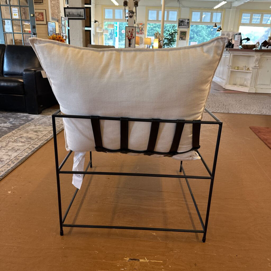 White cushion on a black metal stool in a room with furniture and decor.
