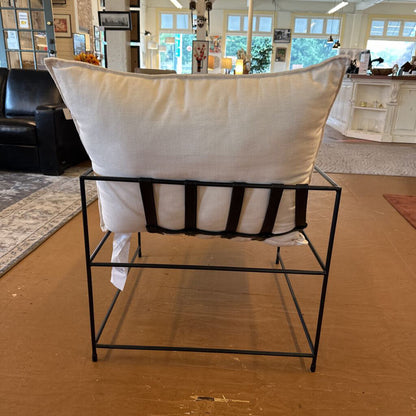 White cushion on a black metal stool in a room with furniture and decor.