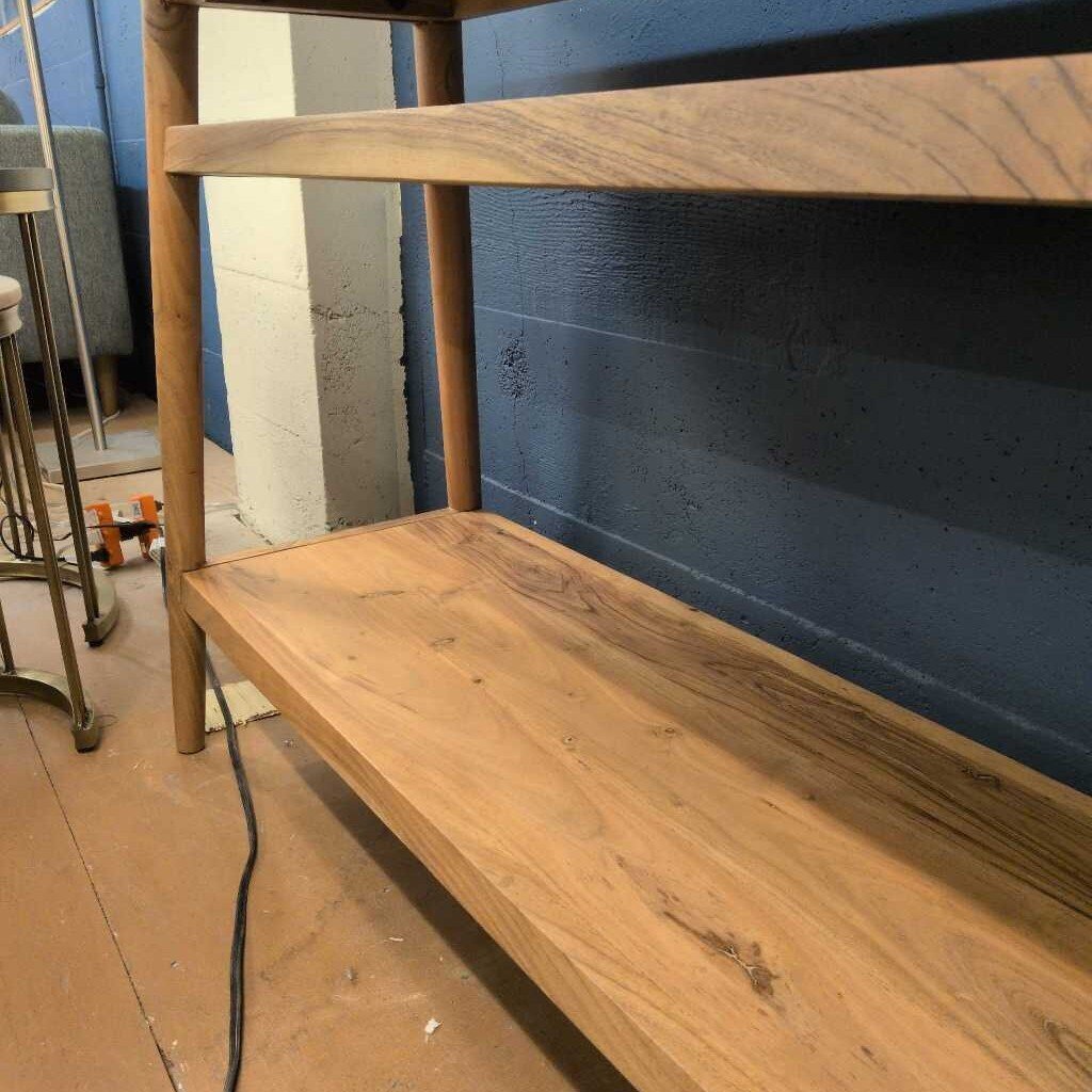 Wooden shelf against a blue wall with a concrete floor.