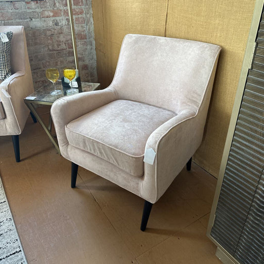 Beige armchair in a room with a brick wall and small table.