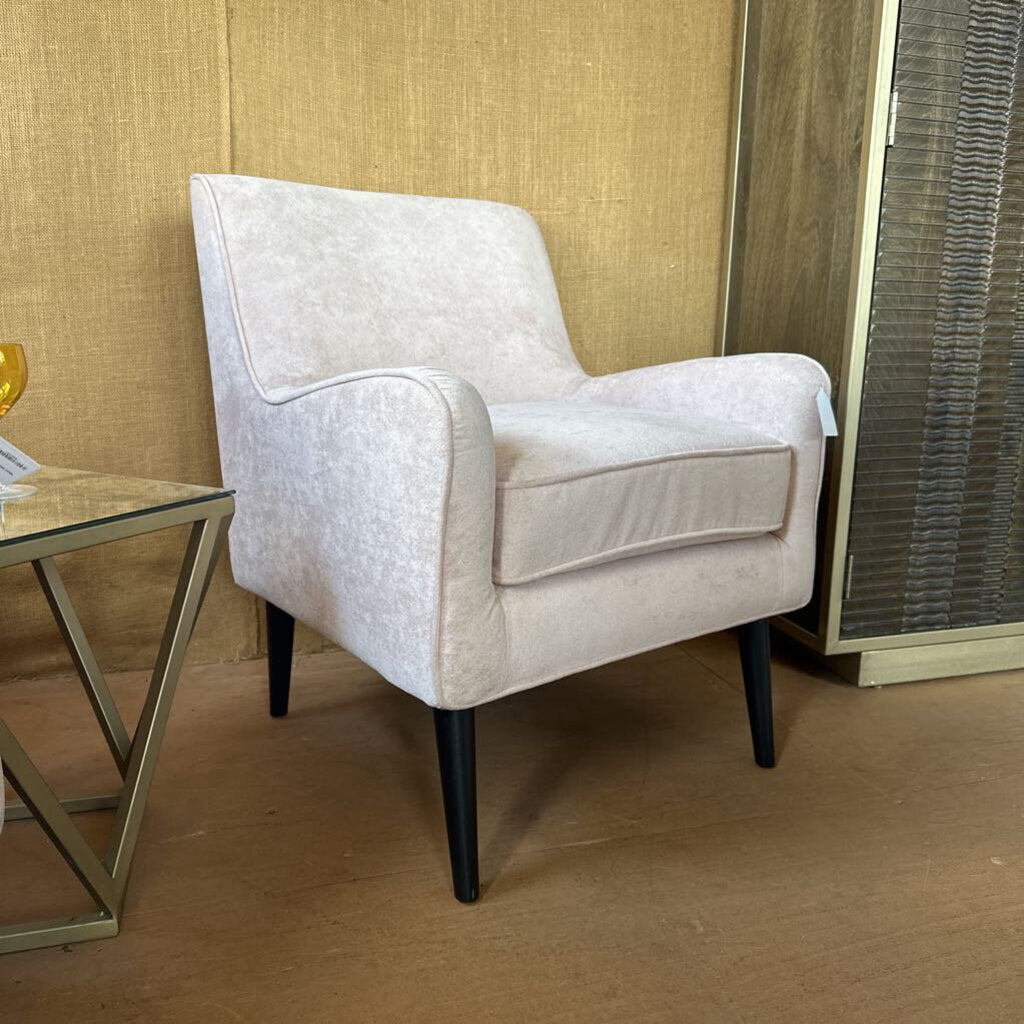 Beige armchair in a room with a textured wall and a small table.