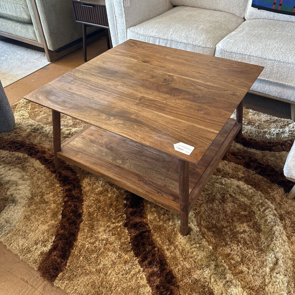 Wooden coffee table in a living room setting with a rug and sofa.