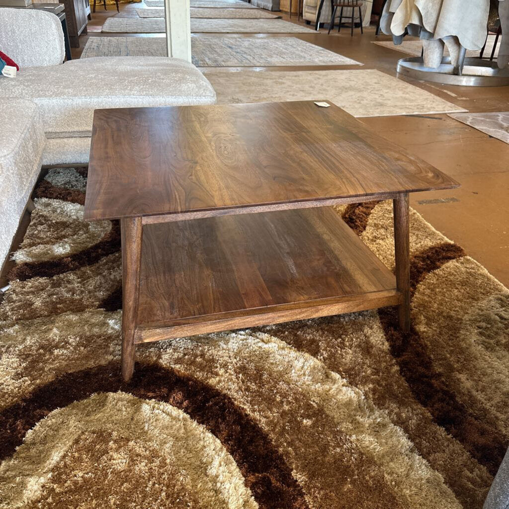 Wooden coffee table on a patterned rug in a showroom setting