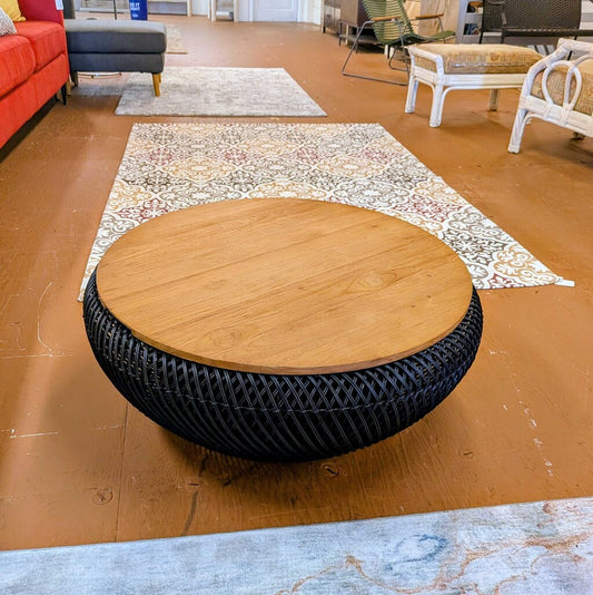Wooden coffee table with black woven base on a brown floor