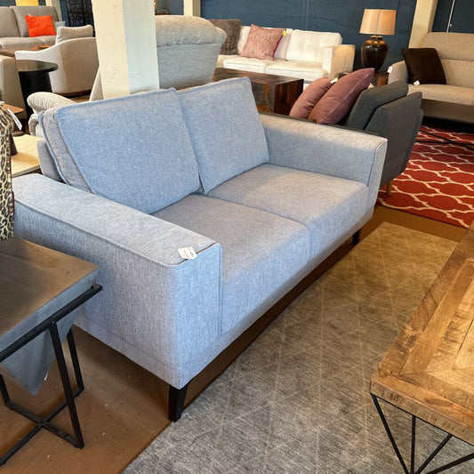 Gray sofa in a showroom with other furniture items.