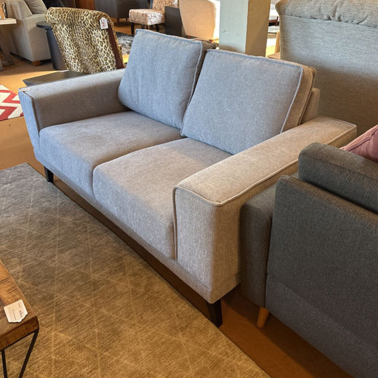 Gray sofa in a room with wooden flooring and other furniture.