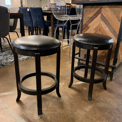 Two black bar stools in a room with tables and chairs.