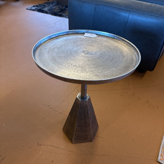 Round metal table with a textured surface on a brown floor.