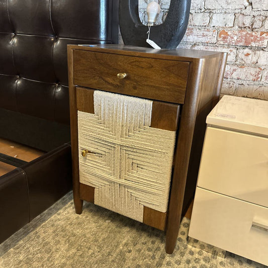 Wooden cabinet with textured panel design next to a leather bench and beige drawer unit.