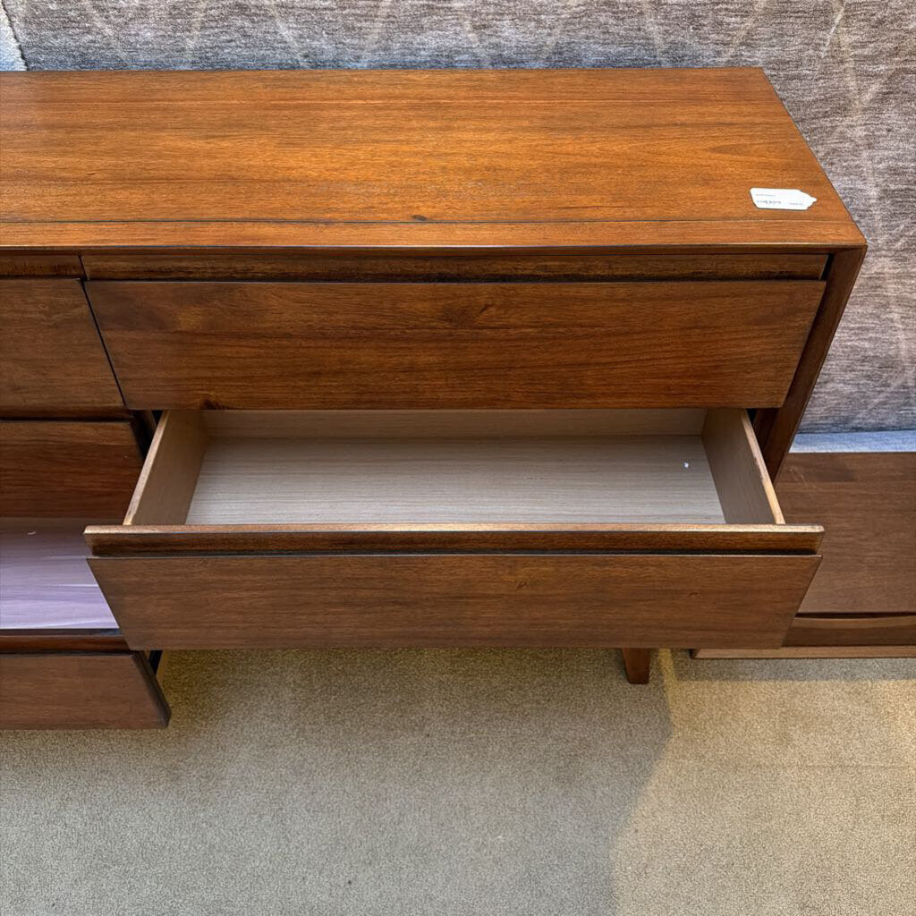 Wooden dresser with an open drawer on a carpeted floor.
