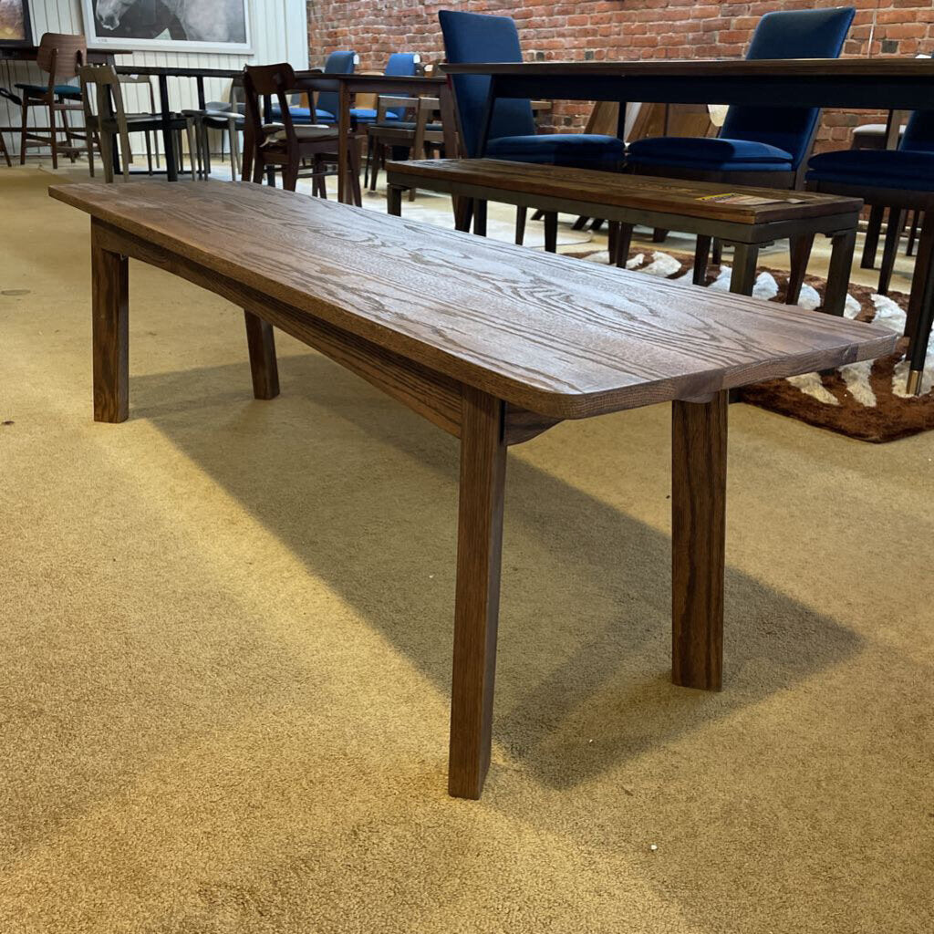 Long wooden table in a room with chairs and a rug.