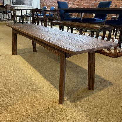 Long wooden table in a room with chairs and a rug.