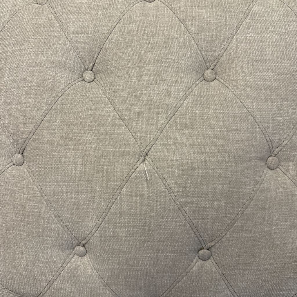 Close-up of a textured gray fabric with diamond pattern and button-like details