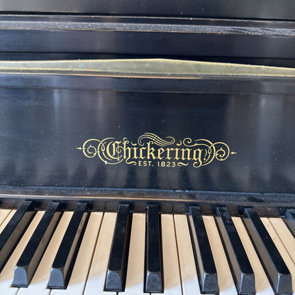 Close-up of a Chickering piano with the brand name and establishment year displayed.