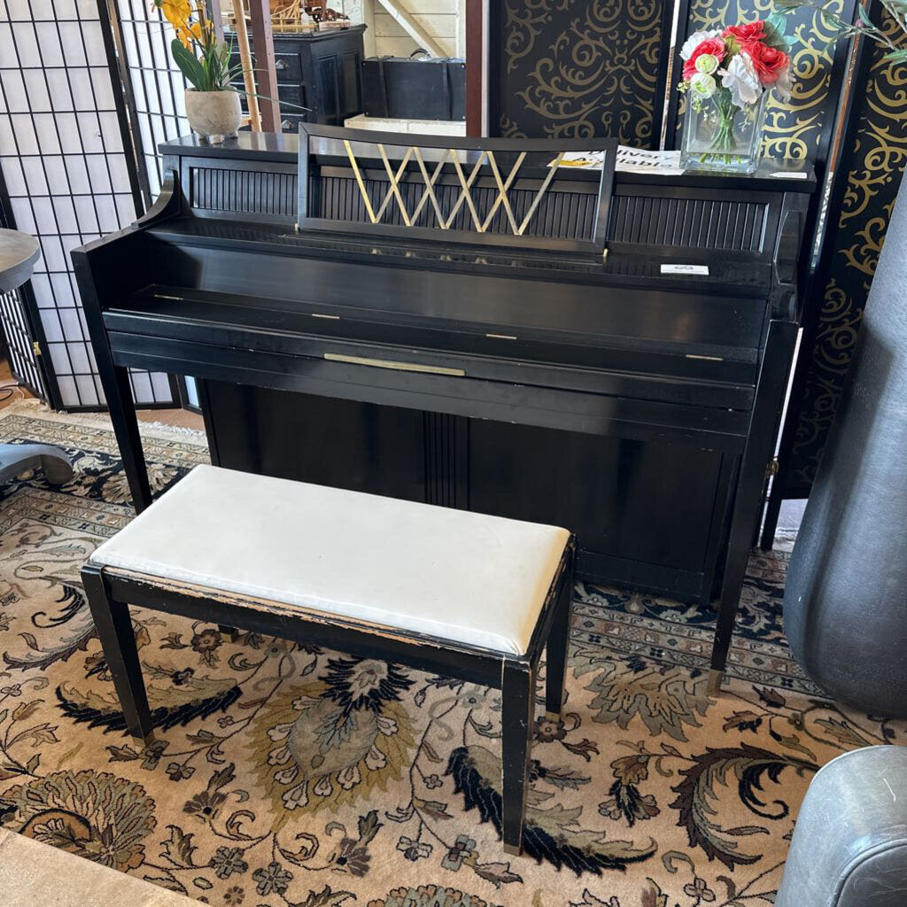 Black upright piano with a bench on a patterned rug