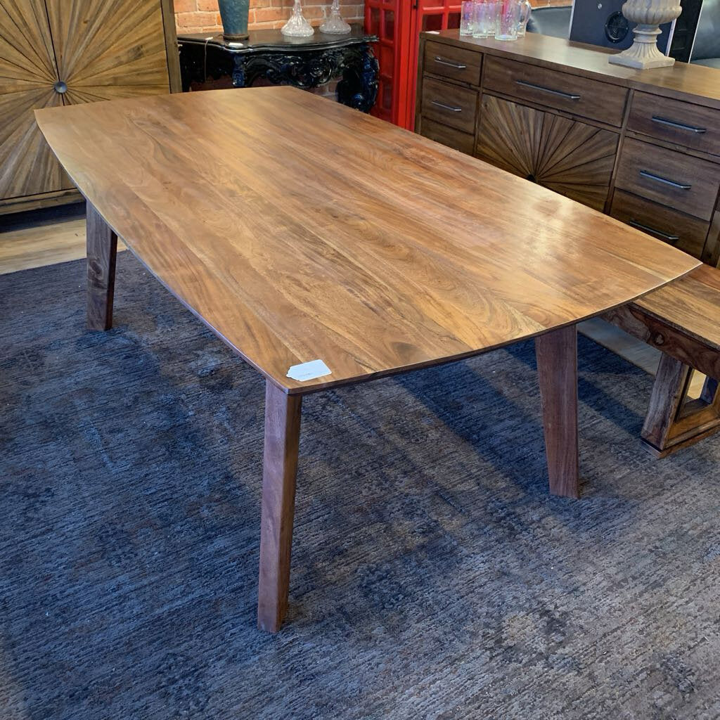 Wooden dining table in a room with a blue carpet and decorative items.