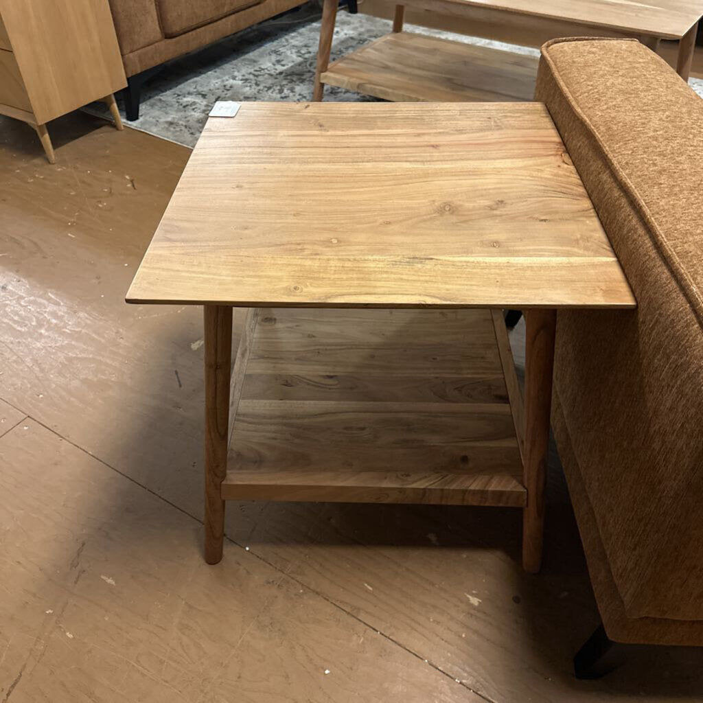 Wooden coffee table with a shelf against a brown sofa on a wooden floor.