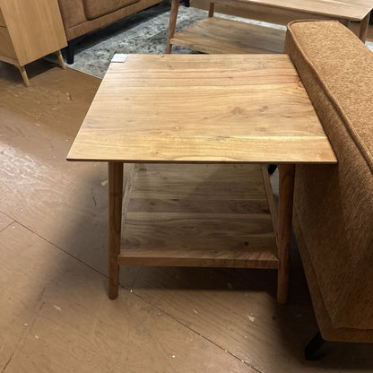 Wooden coffee table with a shelf against a brown sofa on a wooden floor.