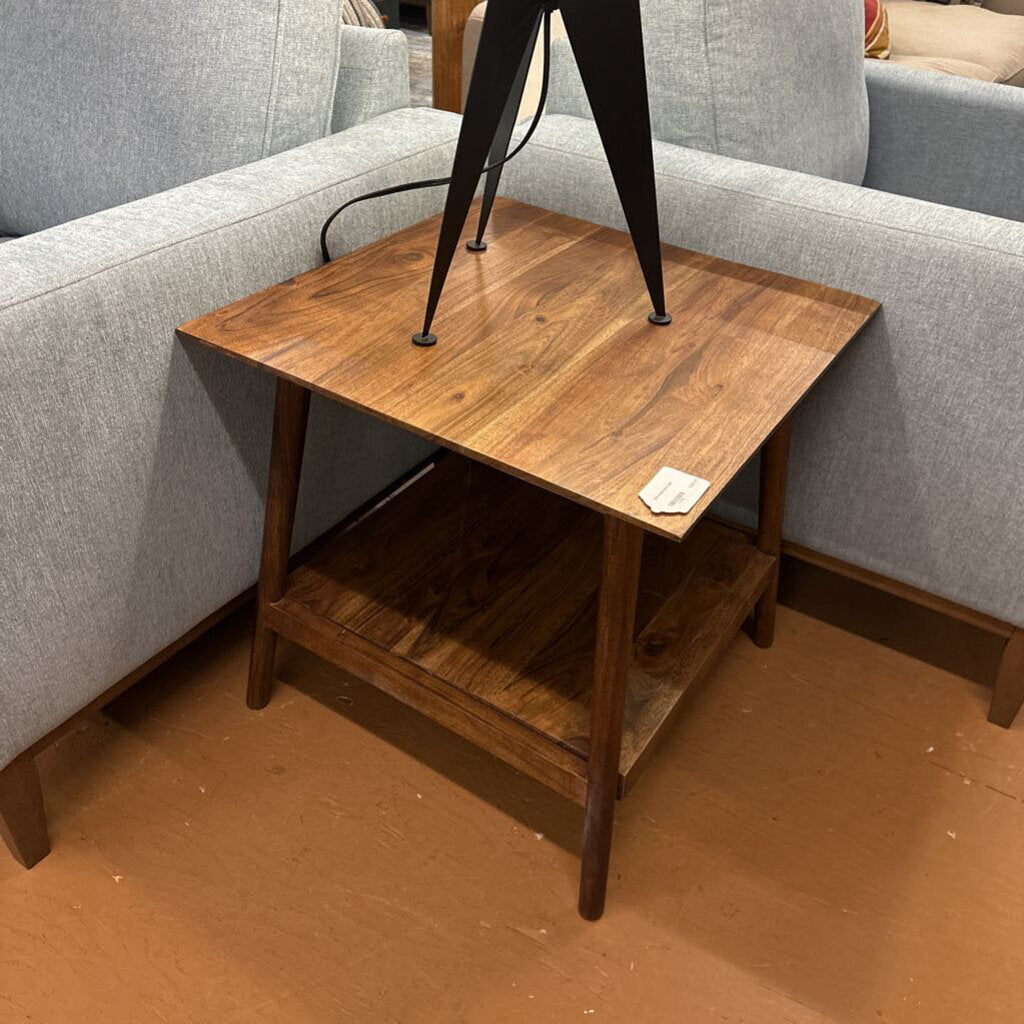 Wooden side table in front of a gray sofa with a lamp on top