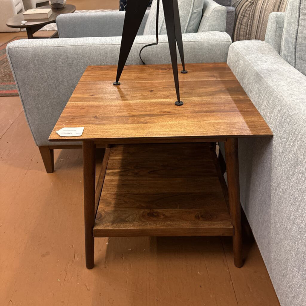 Wooden side table in a living room setting with gray sofa and wooden floor.