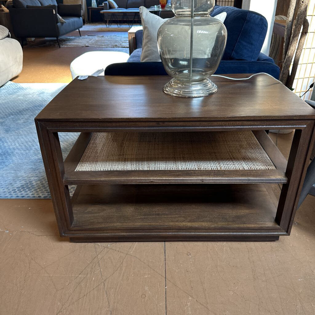 Wooden coffee table with a glass vase on top in a living room setting