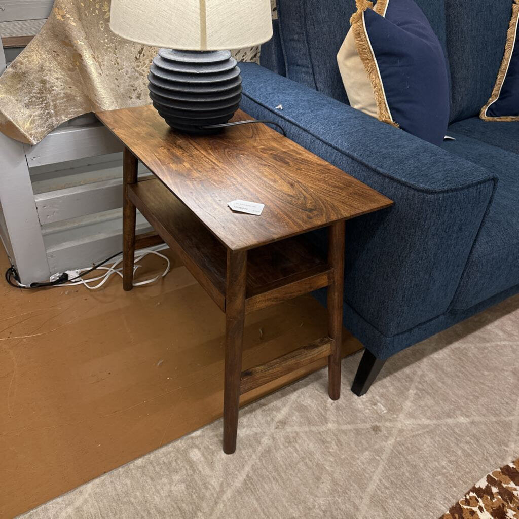 Wooden side table next to a blue sofa with a lamp on top