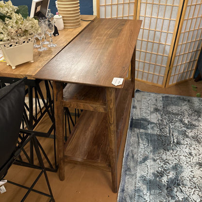 Wooden desk with a chair in a room with a rug and decorative items.