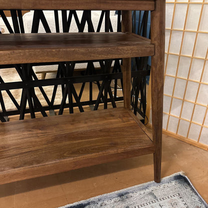 Wooden shelf with two shelves in a room with a rug and decorative wall.